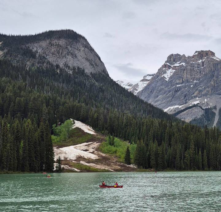 Dense evergreen forest rising up steep rocky mountain slopes partially dusted with snow.