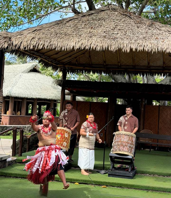 Musicians in traditional attire playing drums on an open-air stage