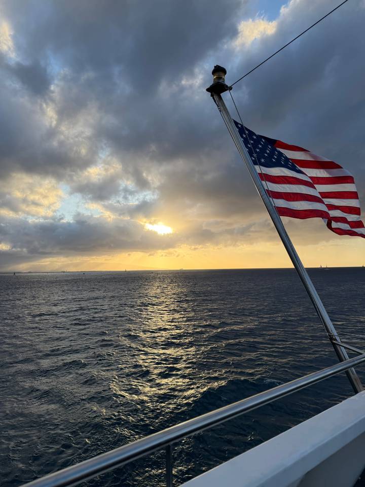American flag on a boat with dramatic sunset over the ocean