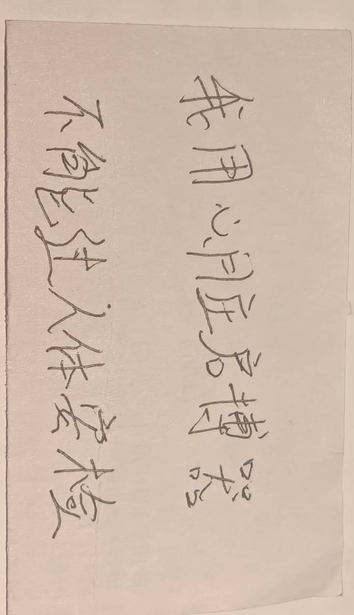 Handwritten Chinese calligraphy on a strip of paper