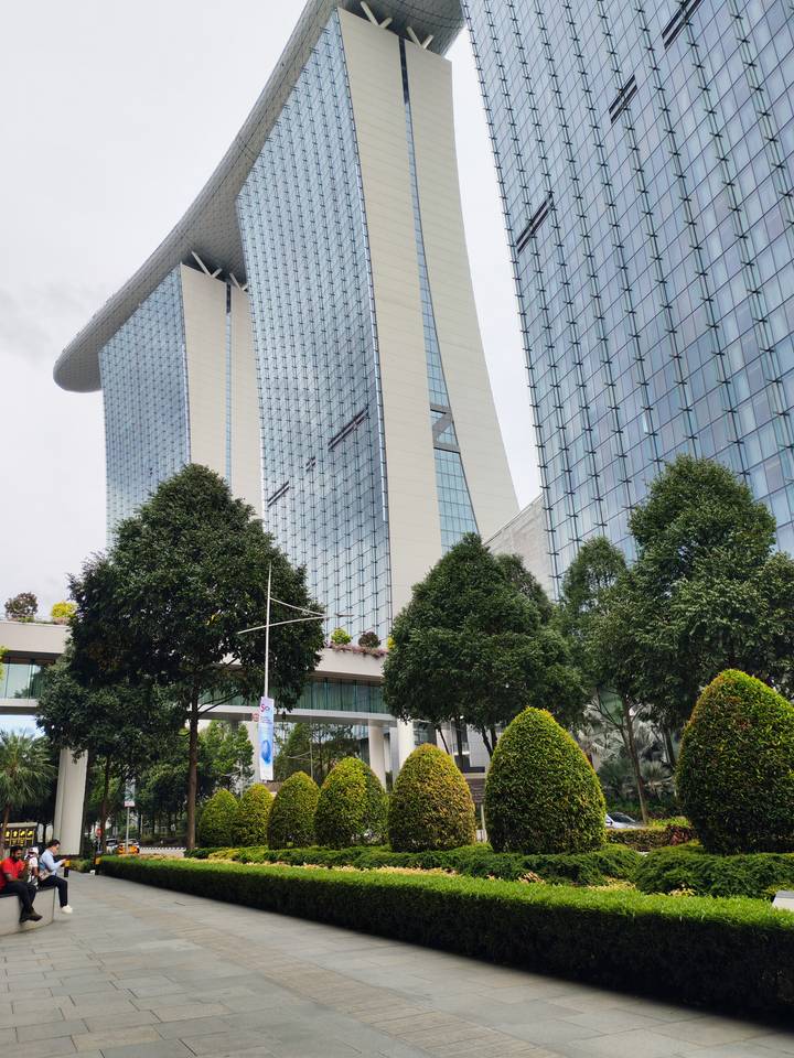 Modern glass towers of Marina Bay Sands complex with greenery in foreground