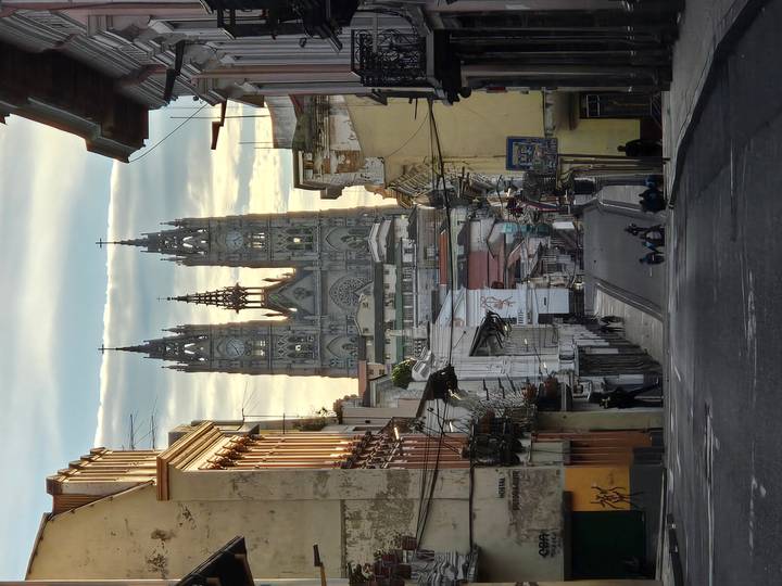 Dramatic perspective down a narrow Quito street toward the towering Basilica del Voto Nacional at dawn.