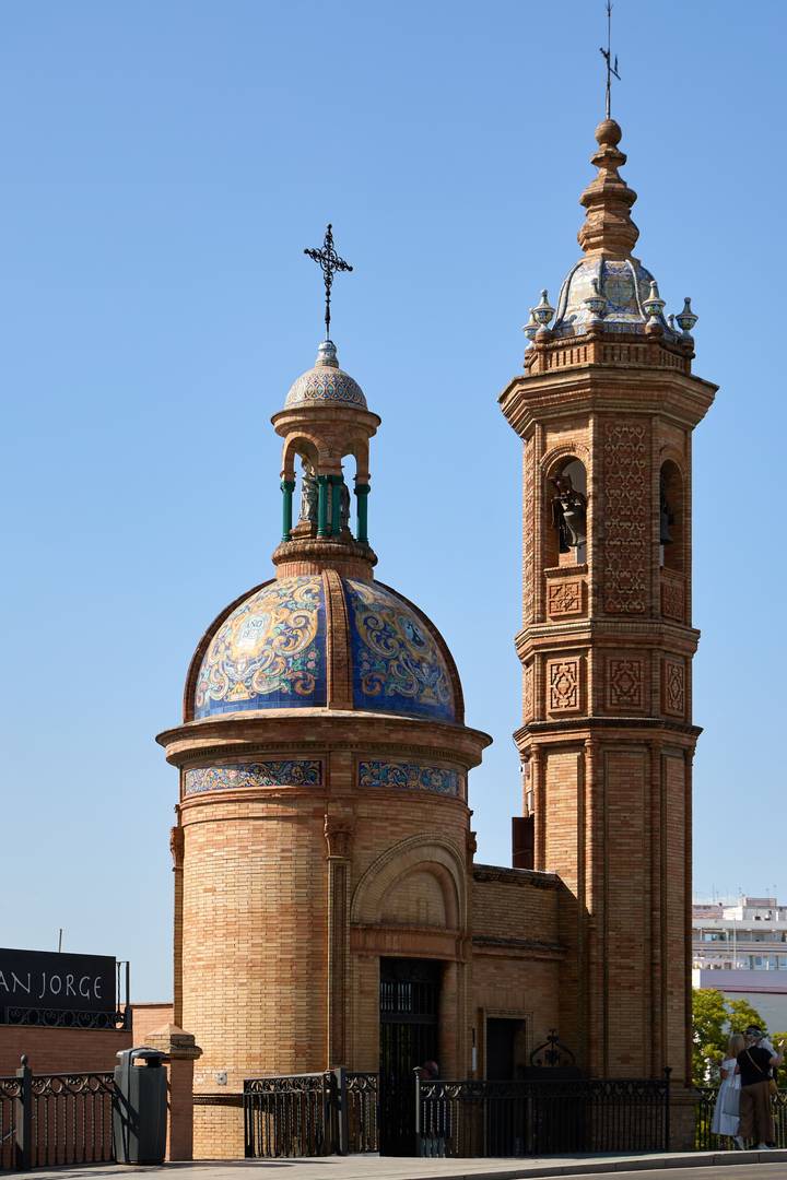 Blue-tiled dome and adjacent brick bell tower against a clear sky.