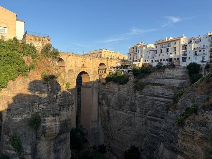 Daylight view of Puente Nuevo spanning the deep gorge with whitewashed town above.