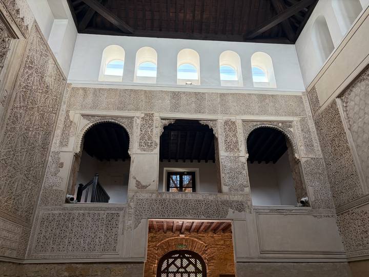 Intricately carved Moorish interior with arched windows and geometric stucco.
