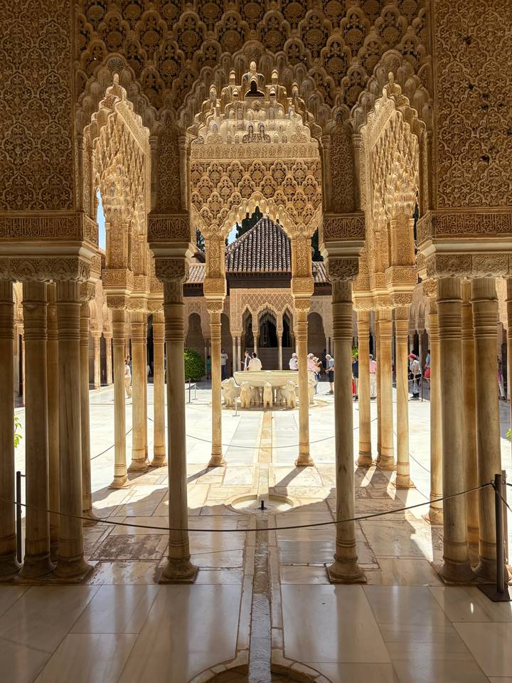 Marble Court of the Lions in the Alhambra framed by ornate Moorish columns.