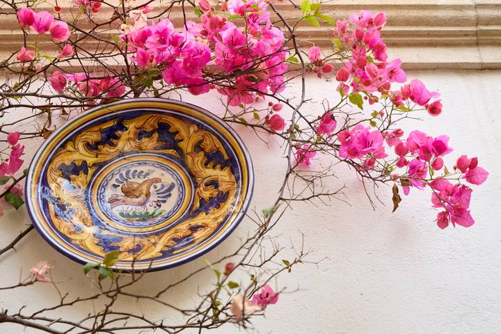 Decorative ceramic plate mounted on a wall with bright pink bougainvillea branches.