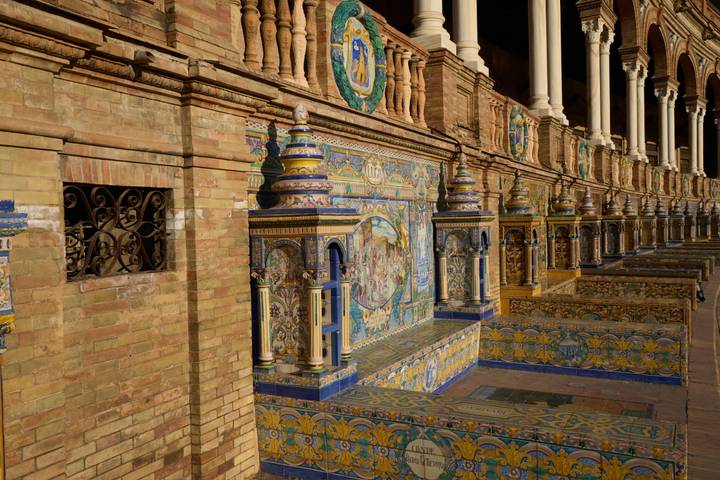 Row of colourful tiled alcoves representing Spanish provinces at Plaza de España.