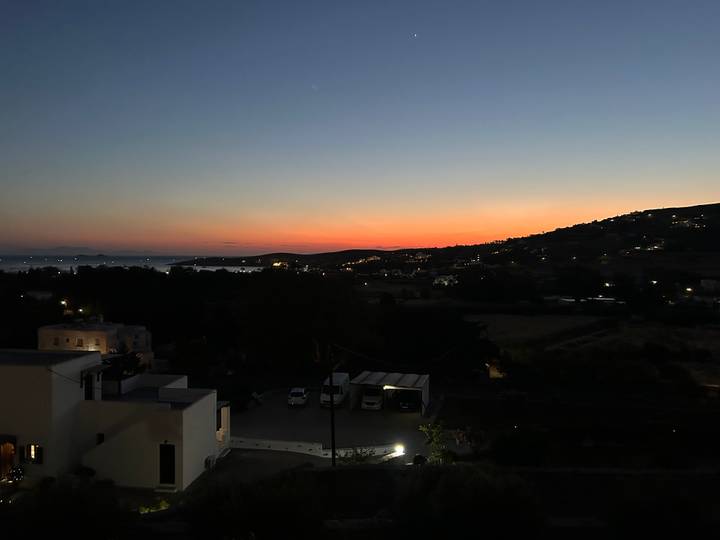 After-sunset panorama with orange glow on the horizon above a dark hillside and scattered village lights.