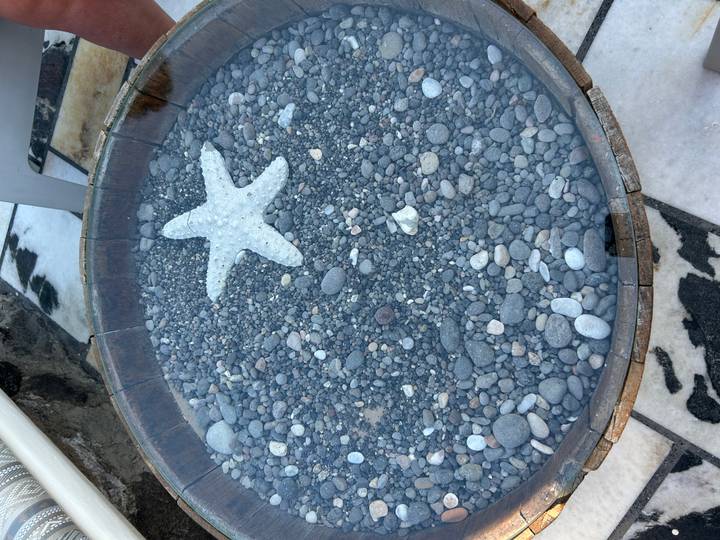 Decorative wooden basin filled with smooth pebbles and a starfish centerpiece.
