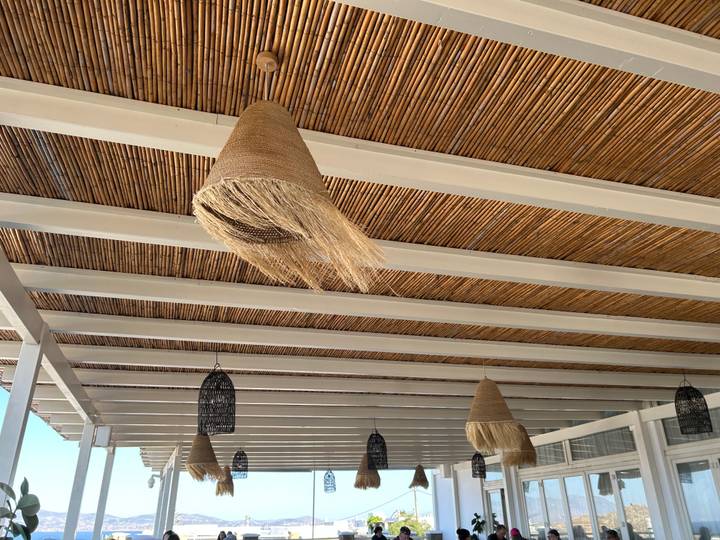 View looking up at a bamboo-covered ceiling with hanging woven lampshades.