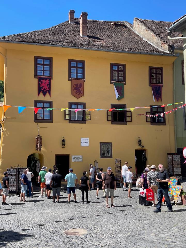Crowds outside the mustard-yellow Vlad Dracul House decorated with medieval banners and bunting.