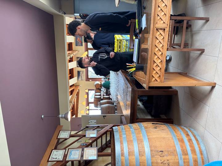 Guests gather in a cozy winery tasting room lined with barrels and glasses prepared for sampling.