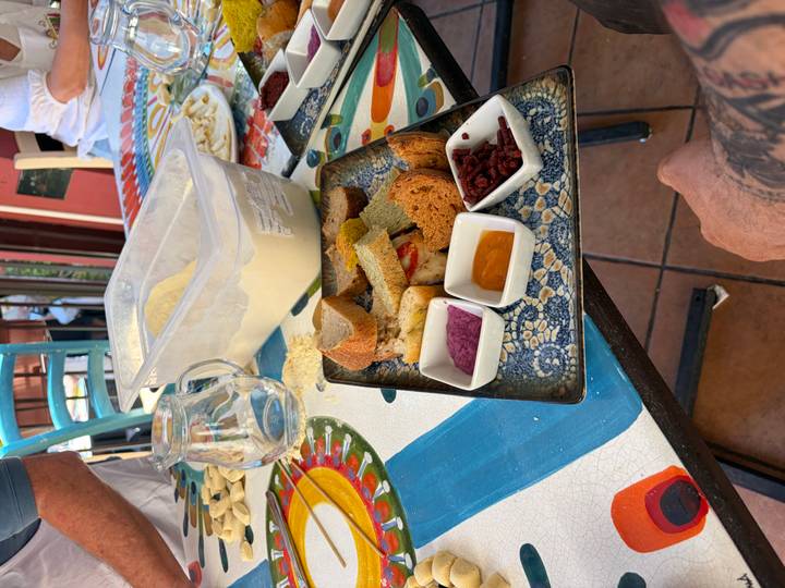 Colourful tasting platter with bread, dips and dried berries on a patterned table during a cooking demonstration