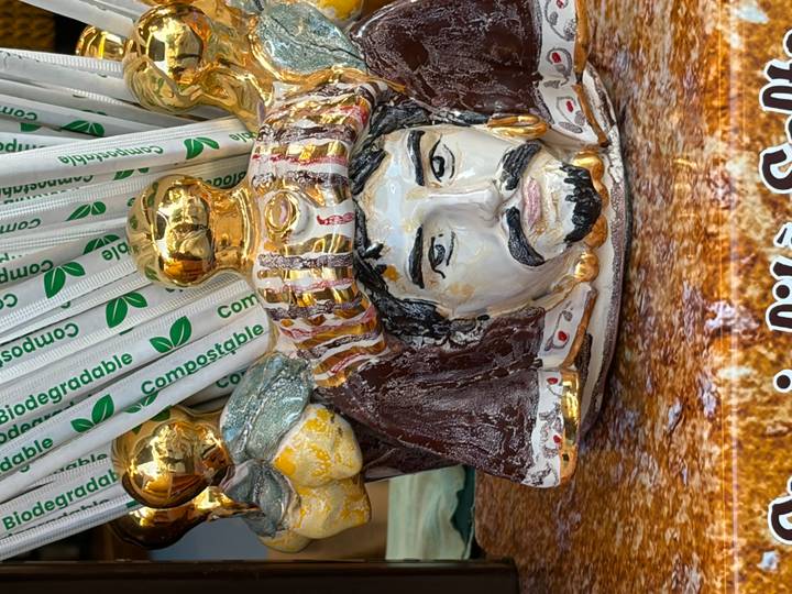 Decorative Sicilian ceramic head filled with gold-topped compostable straws on a market stall