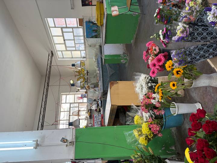 Interior of a florist workshop with colourful bouquets arranged on the floor and workbenches under large windows