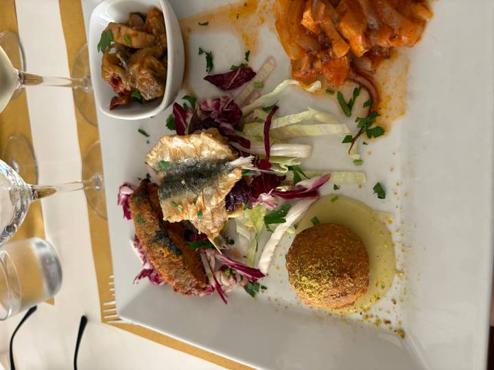 Plated Sicilian mixed starter featuring grilled sardine, eggplant relish and pistachio-coated arancini