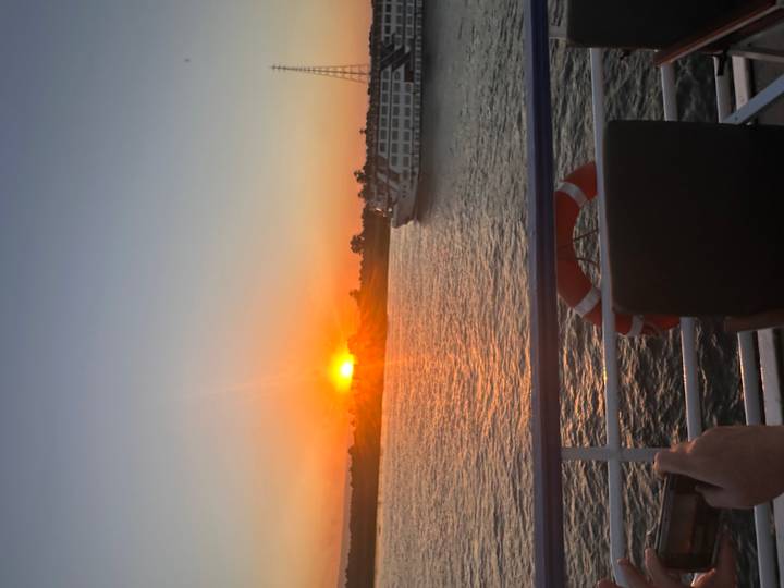 Vibrant sunset over the Nile River with a cruise boat passing by, viewed from a ship railing