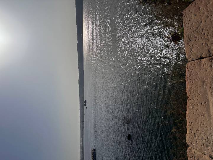 Glittering midday light across a broad lake or reservoir with hazy horizon