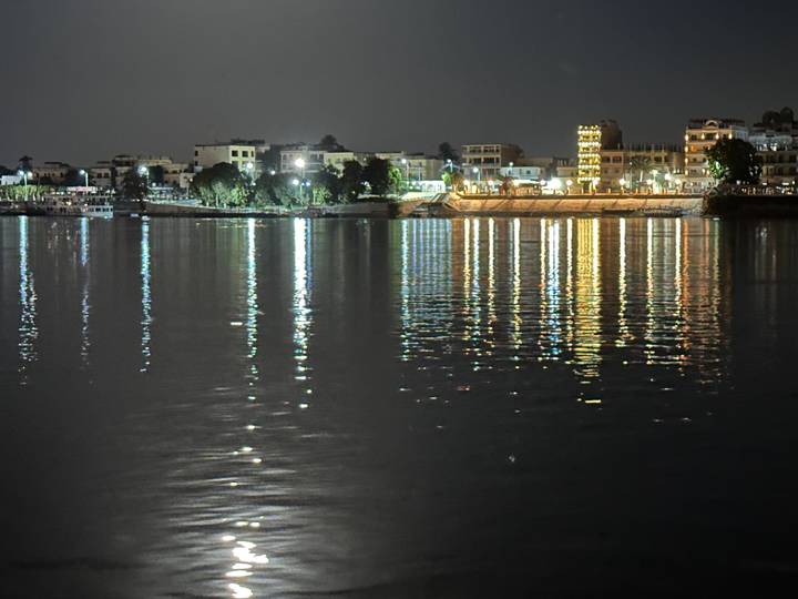Night view of riverside town with colorful light reflections shimmering across water