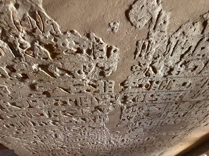 Eroded wall detail with deeply carved hieroglyphic symbols and traces of pigment