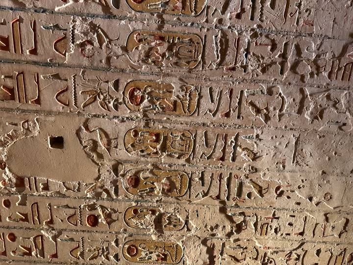 Vertical stone wall with rows of cartouches and hieroglyphs in varying states of preservation