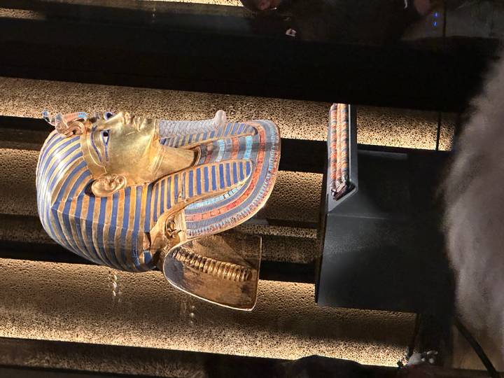 Iconic golden funerary mask of Tutankhamun displayed dramatically under spotlights