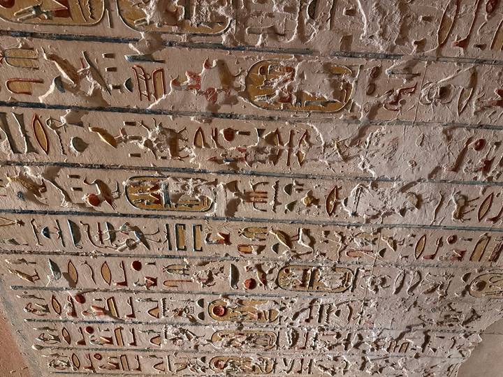 Ancient wall showing vertical rows of hieroglyphs with traces of red and yellow paint