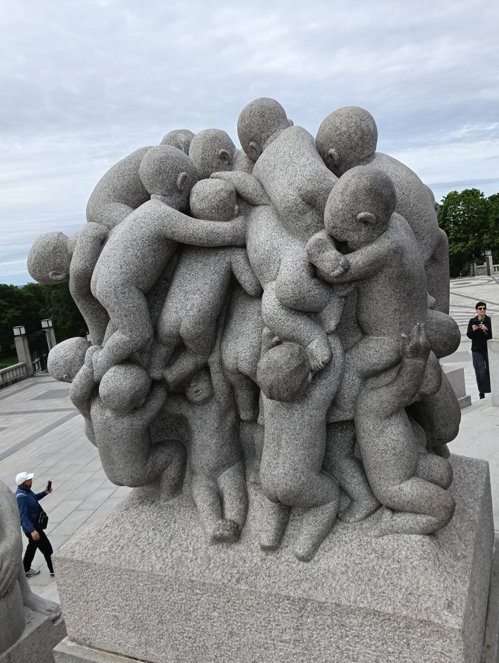 Granite sculpture pile in Vigeland Park fills frame while visitor observes from side.