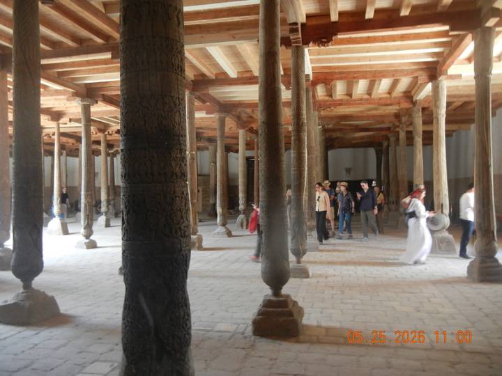 Visitors explore ancient wooden columned hall of Juma Mosque in Khiva.