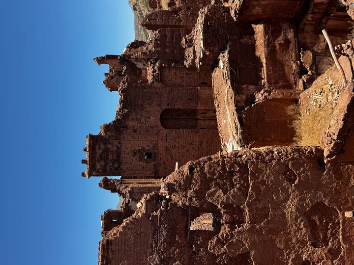 Close-up of weathered red-stone fortress ruins set against a clear blue sky.