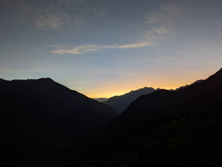 Soft sunrise colors silhouette rugged Andean ridges as daylight breaks over distant peaks.