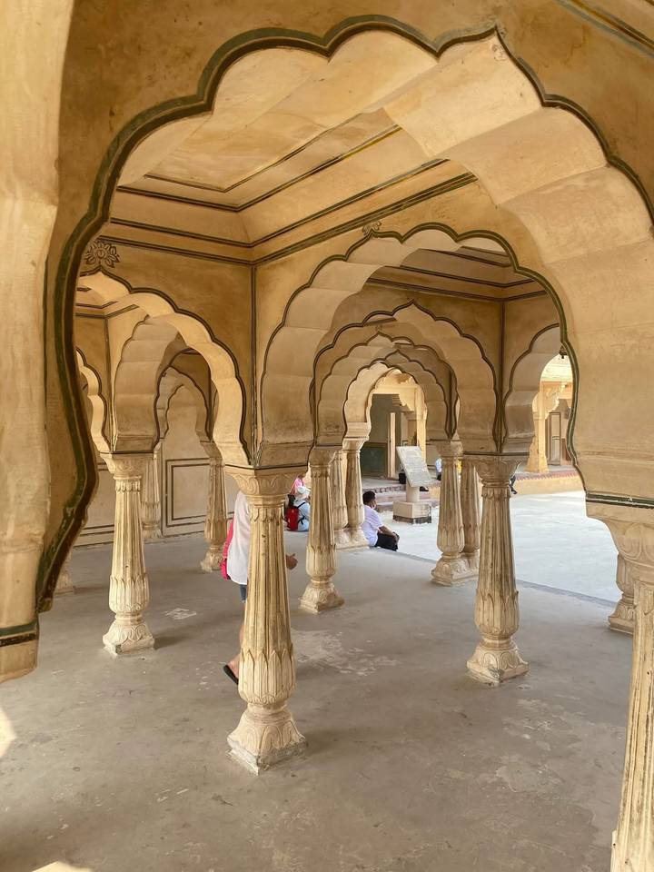 Series of ornate sandstone arches with scalloped edges inside historic fort corridor