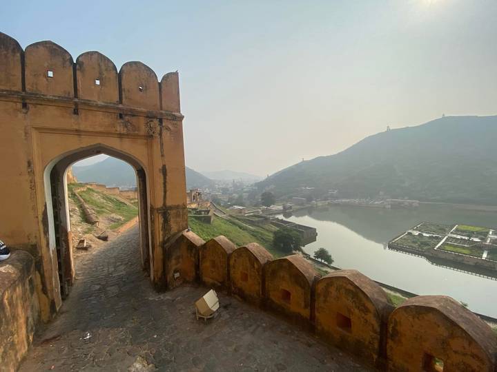 Stone gateway framing hazy valley view over tranquil lake and fortifications at dawn