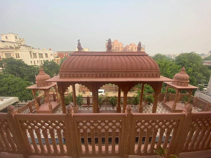 Terracotta-colored rooftop pavilion with small domes overlooking leafy suburb