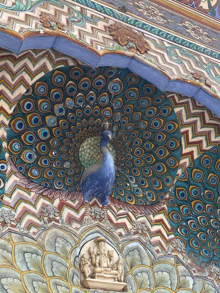 A vibrant Peacock Gate with intricate feather patterns and a sculpted peacock at Jaipur’s City Palace.