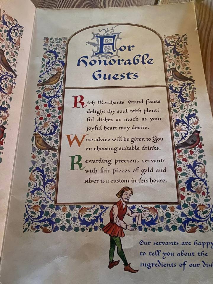Decorative medieval-style menu page with illuminated letters and floral border.
