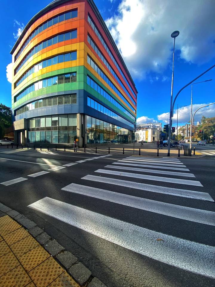 Colorful modern glass office block on a bright sunny corner with zebra crossing.