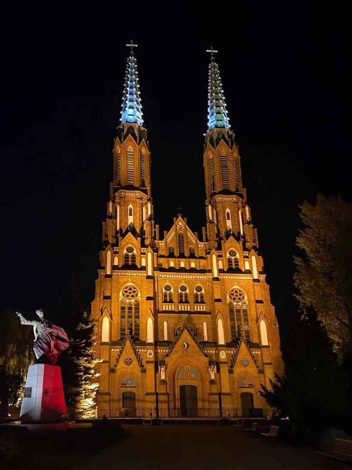 Twin-towered brick church dramatically illuminated against a dark night sky.