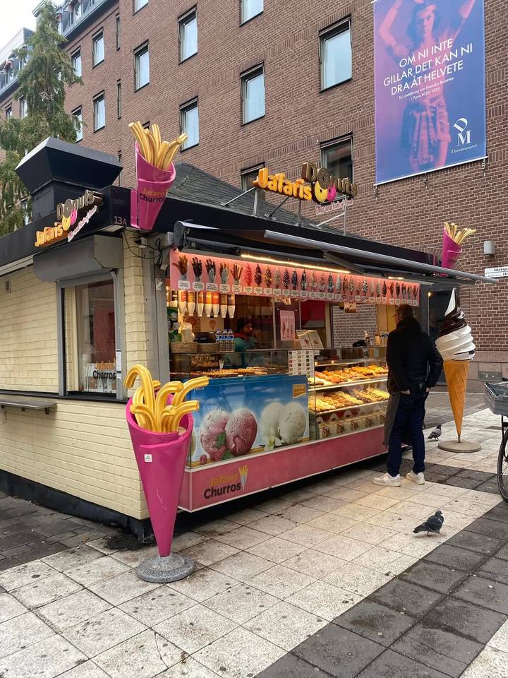 Street kiosk selling waffles, churros and ice cream with colorful displays.