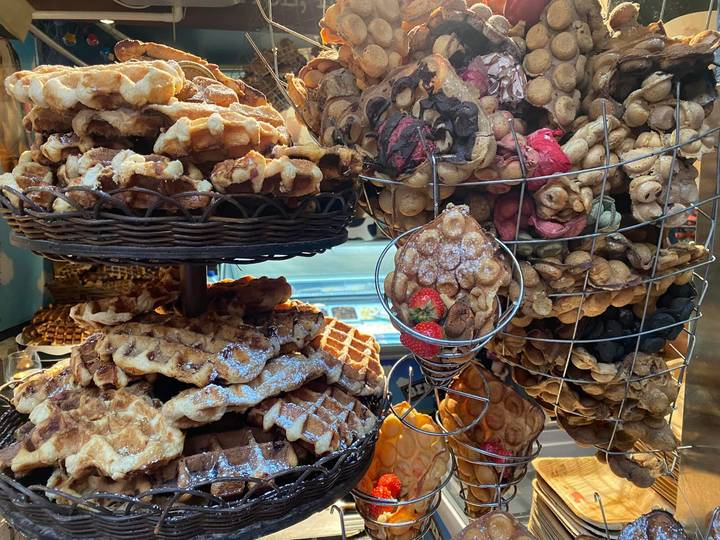 Baskets stacked high with freshly baked waffles and bubble waffles dusted with sugar.