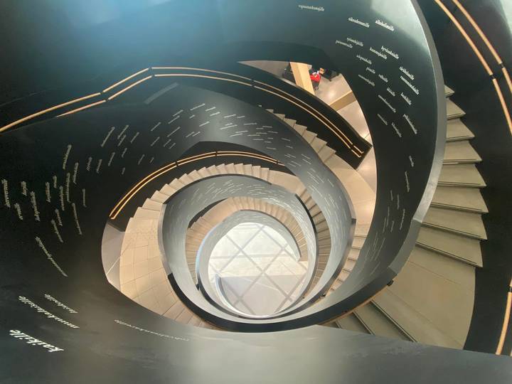 Interior view looking down a striking black spiral staircase with text along the rails.