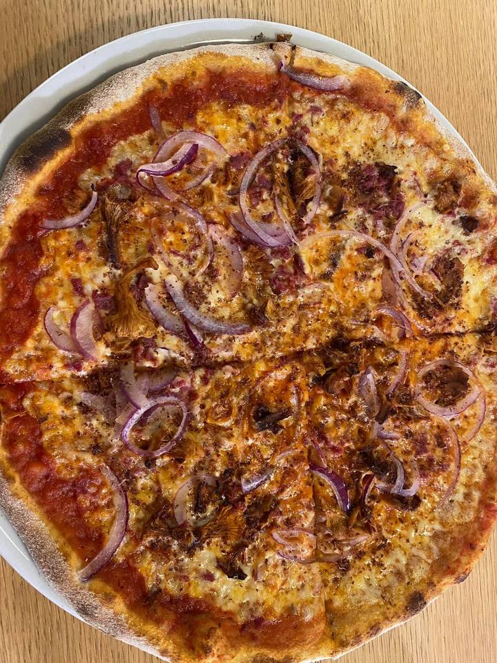 Close-up of a rustic pizza topped with chanterelle mushrooms and red onion slices.