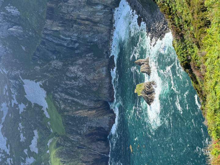 Rocky sea stacks surrounded by vivid turquoise waves at rugged coastline