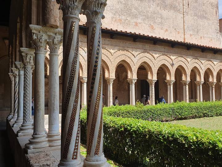 Cloister with elegant marble columns and arches, visitors strolling in the courtyard.
