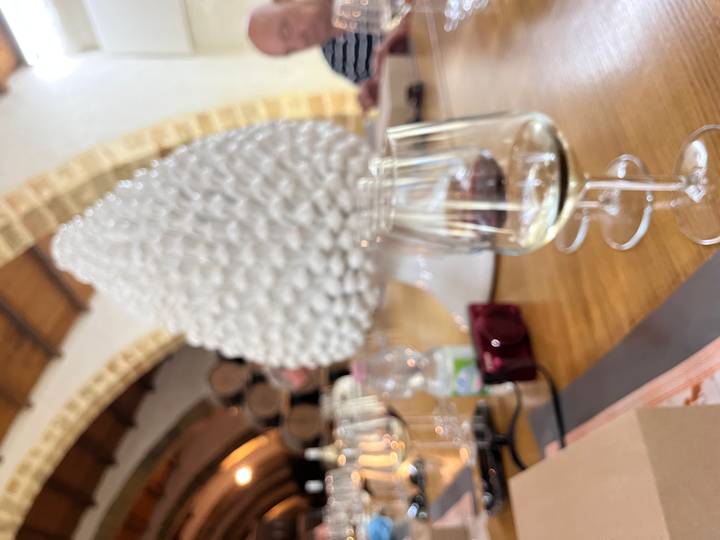 Blurred close-up of wine glasses and a ceramic pine-cone ornament on a tasting table.