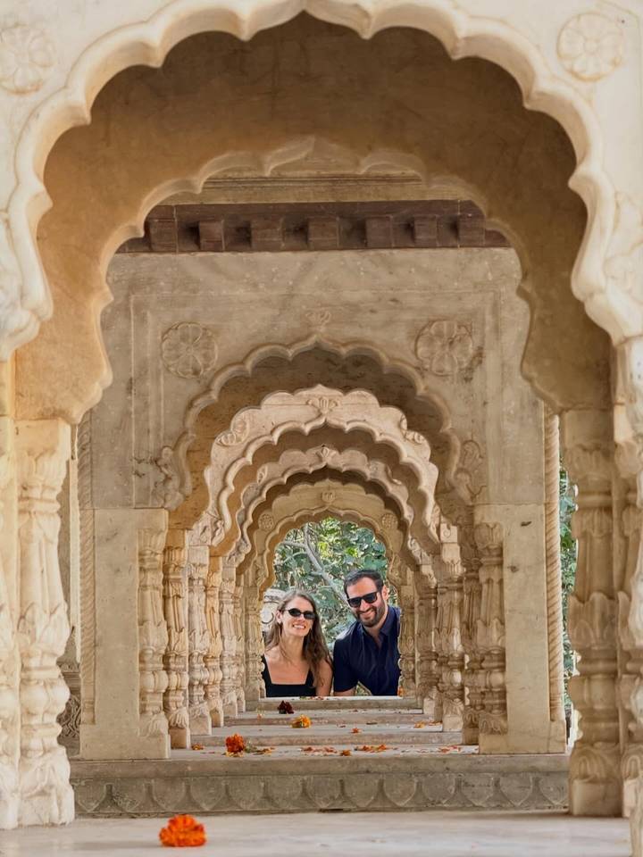 Couple framed by a series of ornate scalloped sandstone arches in Jaipur.