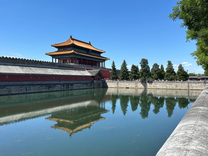 Moat reflection of the Forbidden City’s corner tower under a clear blue Beijing sky.
