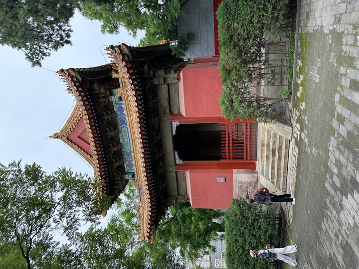 Small traditional red pavilion with ornate roof tiles inside Beijing’s temple grounds.