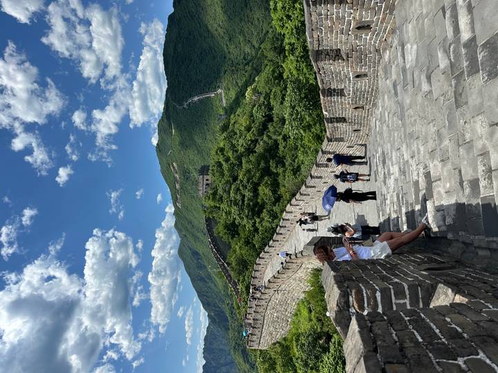 Stone steps and crenellated walls winding over green mountains on the Great Wall of China.